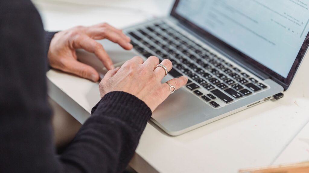 Close-up of hands typing on a laptop in a clean, modern workspace.