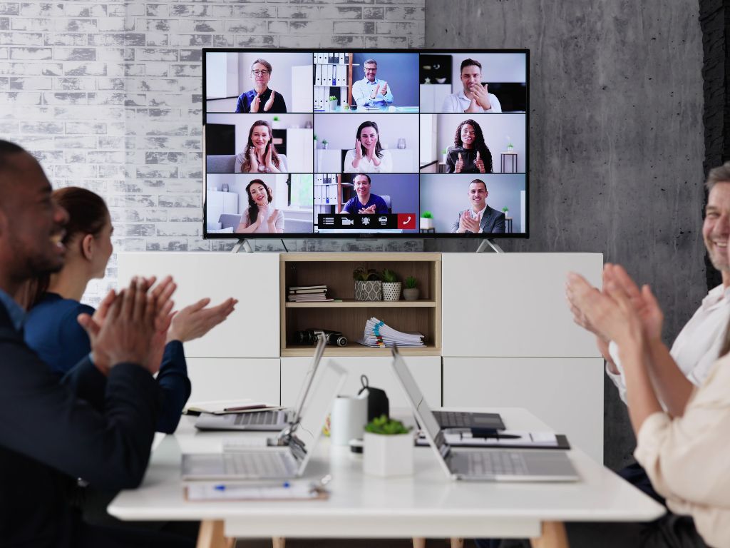 Facilitator leading a corporate coaching workshop in a modern conference room with Zoom call.