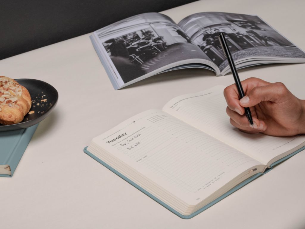 Person using a Full Focus Planner at a minimalist desk with natural light and green accents.
